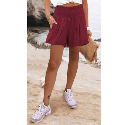 High waist shorts in burgundy, worn by a person on a sandy beach.