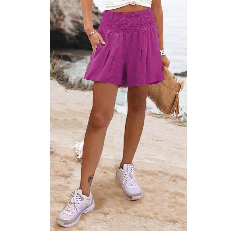 Woman wearing purple high waist shorts on beach.